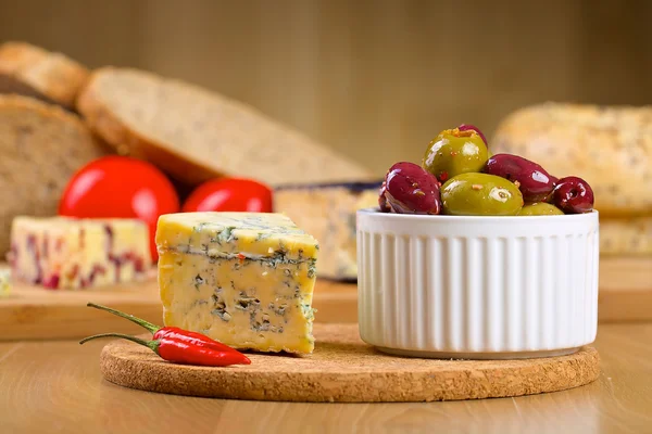 Queijo azul e azeitonas numa tábua de madeira — Fotografia de Stock