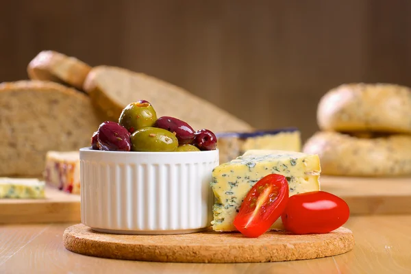 Queijo azul e azeitonas numa tábua de madeira — Fotografia de Stock