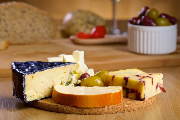 Various cheese and olives on a wooden board — Stock Photo, Image