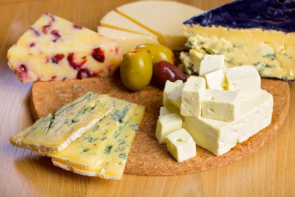 Various cheese and olives on a wooden board — Stock Photo, Image