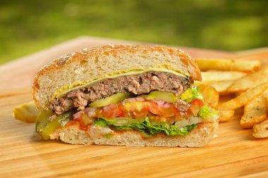 Eritilmiş peynir ve kalın etli zemin sığır patty, marul, domates, soğan, ahşap masa üzerinde duran susam çörek ile düzenlenen burger