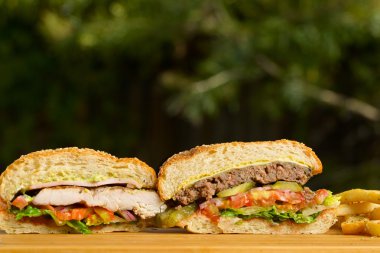 Eritilmiş peynir ve kalın etli zemin sığır patty, ızgara tavuk, marul, domates, soğan, susam çörek ahşap masa üzerinde duran iki düzenlenen Burger