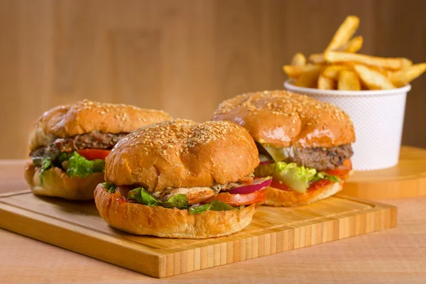 Sabrosa hamburguesa con queso derretido y gruesa suculenta empanada de pollo molido, lechuga, tomate, cebolla, pan de sésamo de pie sobre una mesa de madera —  Fotos de Stock