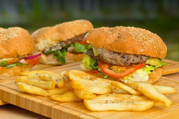 Smaczny hamburgera z serem i grube soczyste ziemi patty wołowiny, sałata, pomidor, cebula, sezam bułka stojąc na drewnianym stole — Zdjęcie stockowe