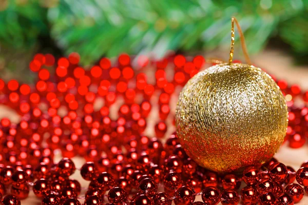 Yellow christmas ball on red beads — Stock Photo, Image