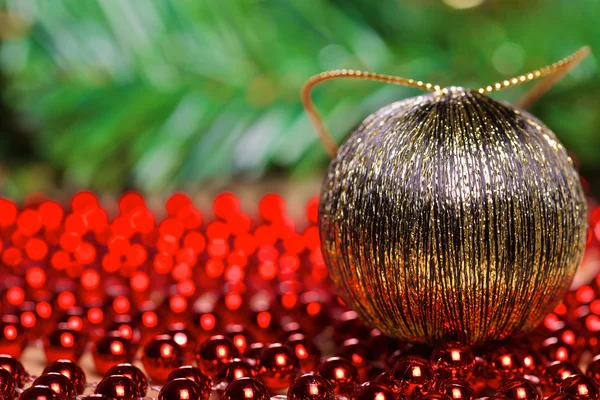 Yellow christmas ball on red beads — Stock Photo, Image