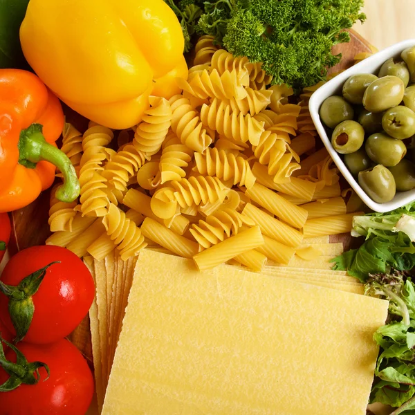 Variety of uncooced italian pasta on wooden table — Stock Photo, Image