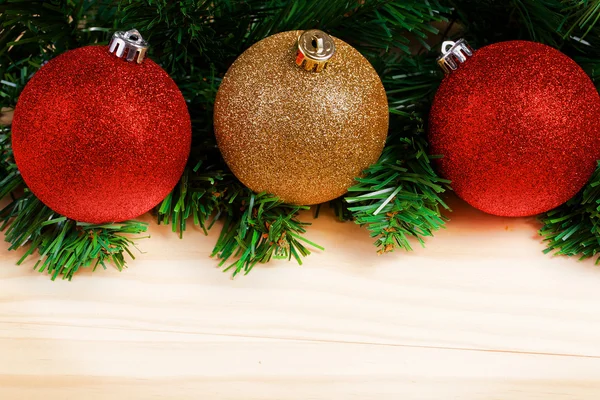 Weihnachtskugeln mit Tannenzweigen auf Holzgrund — Stockfoto