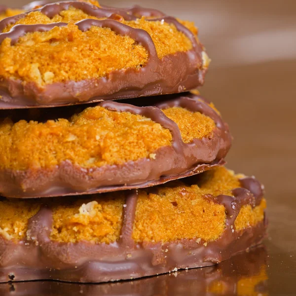 チョコレート ストリップ黄色の光沢紙の上とブラウン クッキーの山 — ストック写真