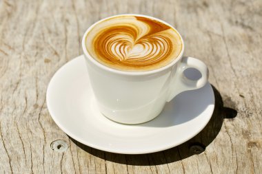 Kalp şeklinde köpük ile beyaz bir fincan CAPUCINO veya sütlü kahve