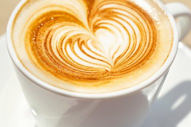 Kalp şeklinde köpük ile beyaz bir fincan CAPUCINO veya sütlü kahve