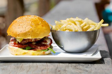 Eritilmiş peynir ve kalın etli zemin sığır patty, marul, domates, soğan, ahşap tahta üzerinde duran susam çörek ile lezzetli burger