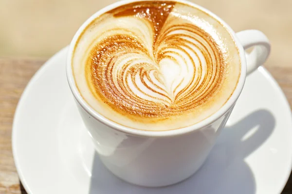 Cappuchino or latte coffe in a white cup with heart shaped foam — Stock Photo, Image