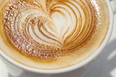 Kalp şeklinde köpük ile beyaz bir fincan CAPUCINO veya sütlü kahve