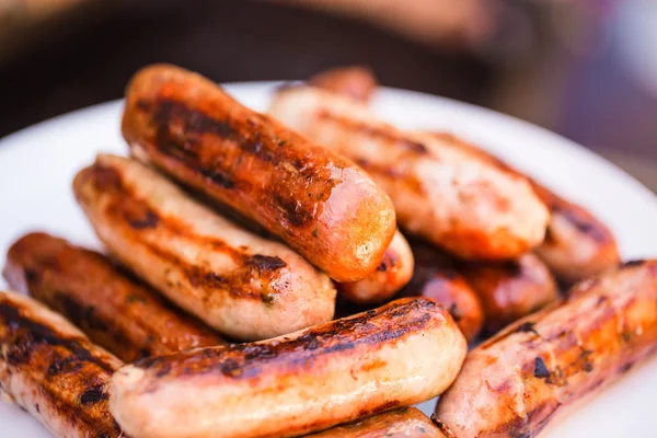 Carne alla brace e salsicce di maiale su piatto bianco — Foto Stock