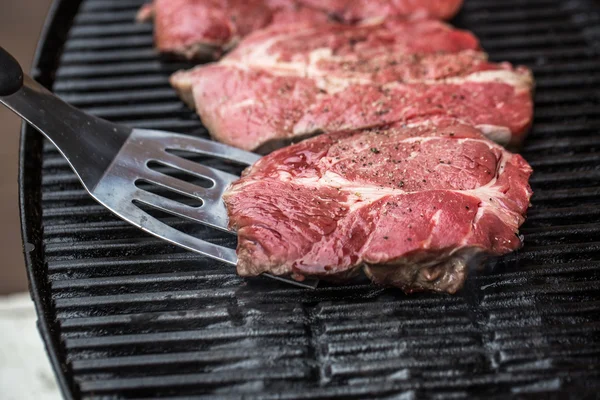 Beef steaks on grill or BBQ with spatula — Stock Photo, Image
