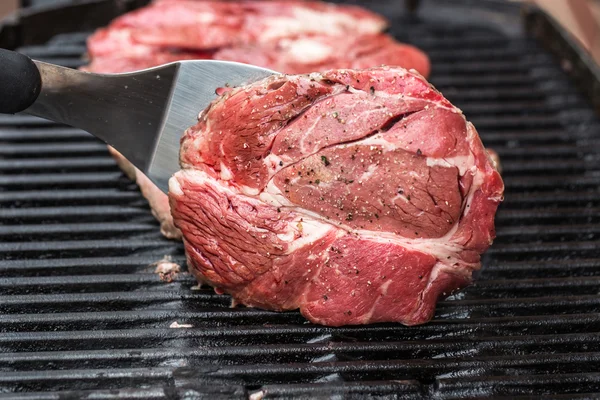 Beef steaks on grill or BBQ with spatula — Stock Photo, Image