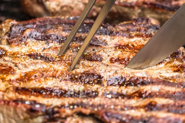 Bifes de carne na grelha com garfo e faca para churrasco Imagem De Stock