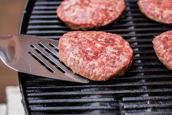 Burger de carne de vită la grătar pe spatulă împotriva grătarului — Fotografie, imagine de stoc