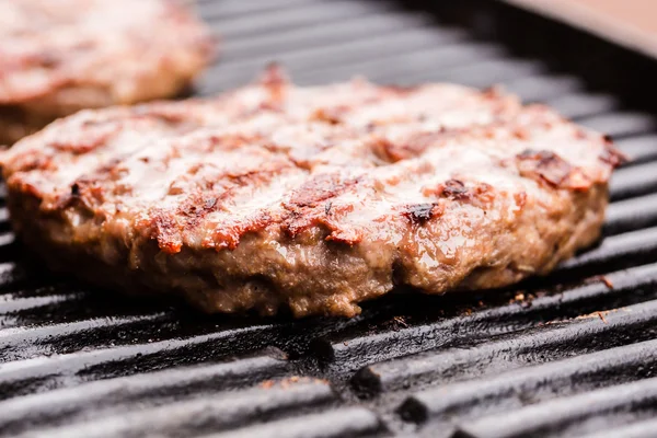 Preparing a batch of  grilled ground beef patties or frikadeller on BBQ