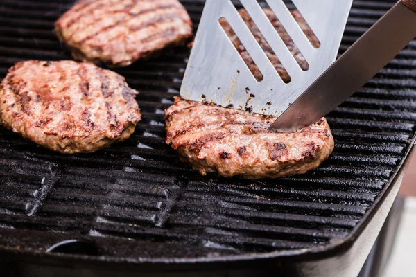 Hamburger di polpette di manzo alla griglia con spatola e coltello sul barbecue — Foto Stock