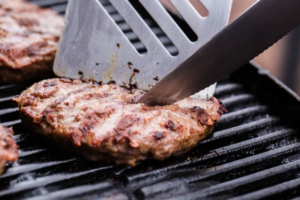 Hamburger di polpette di manzo alla griglia con spatola e coltello sul barbecue — Foto Stock