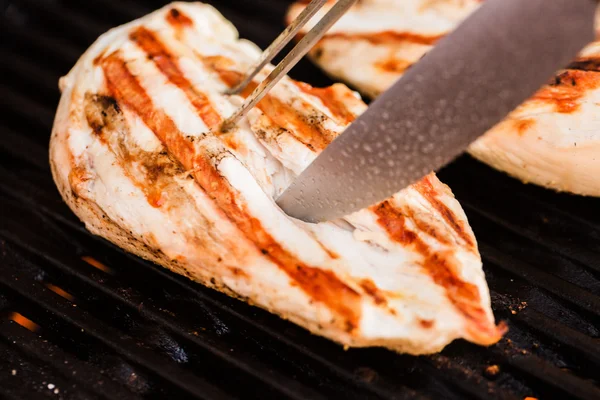 Grilled chicken breast fillets on BBQ with fork and knife — Stock Photo, Image