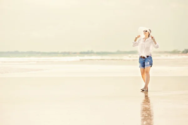 Młoda kobieta trzymać spaceru wzdłuż plaży w słoneczny dzień enjoing wakacji — Zdjęcie stockowe