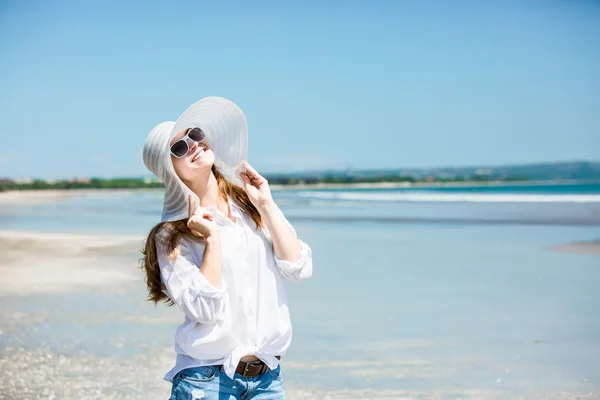 Beautiful young woman walking along the beach at sunny day enjoing summer vacation — стоковое фото