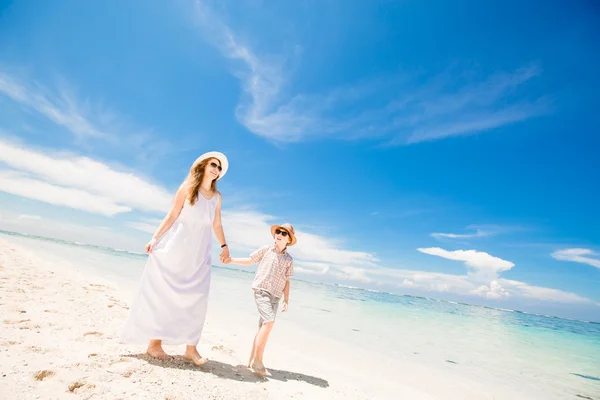 Gelukkig mooie jonge moeder en zoon genietend van strand tijd met blauwe lucht boven de Oceaan op backgrund — Stockfoto