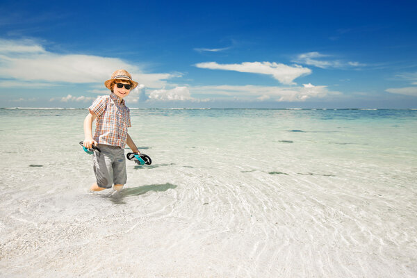 Счастливый мальчик, живущий в океанской воде на прекрасном пляже в шляпе и солнцезащитных очках
.
