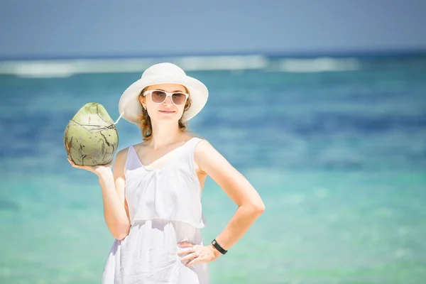 Красивая молодая женщина держит и пьет кокосовый свежий коктейль в тропическом море — стоковое фото