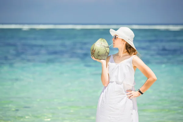 Frumoasă femeie tânără care ține și bea un cocktail proaspăt de nucă de cocos în marea tropicală — Fotografie, imagine de stoc