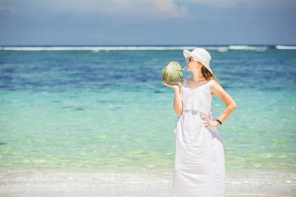 Bella giovane donna che tiene e beve un cocktail fresco di cocco nel mare tropicale — Foto Stock