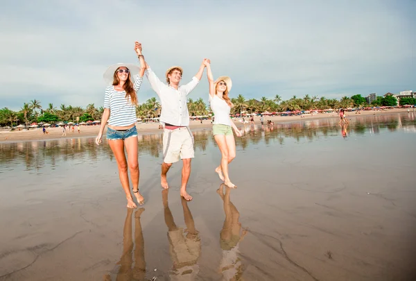Група щасливих молодих людей, що гуляють вздовж пляжу на красивому літньому заході сонця — стокове фото
