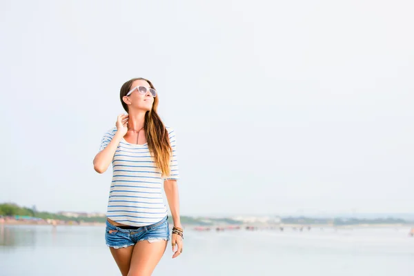 Beautifil joven mujer caminando a lo largo de la playa al atardecer disfrutando de vacaciones de verano — Foto de Stock