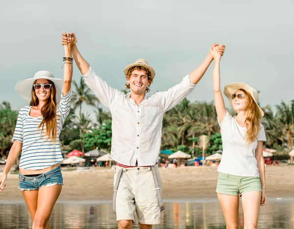 Grupo de jóvenes felices caminando por la playa en el hermoso atardecer de verano —  Fotos de Stock