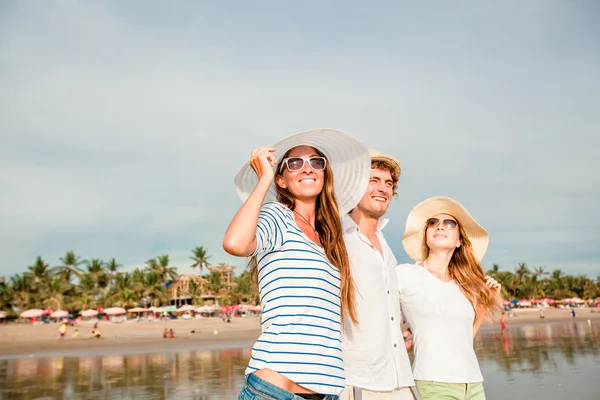 Groep van gelukkige jonge mensen lopen langs het strand op een mooie zomerse zonsondergang — Stockfoto