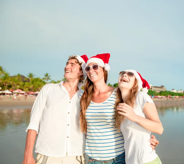 Grupo de jovens felizes em chapéus de christmass na praia — Fotografia de Stock