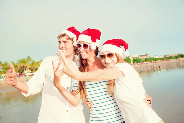 Gruppo di giovani felici in cappelli di Natale sulla spiaggia — Foto Stock