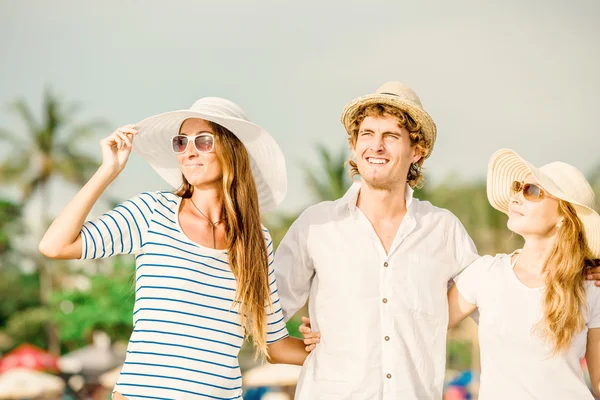 Group of happy young people walking along the beach on beautiful summer sunset — Stock Photo, Image