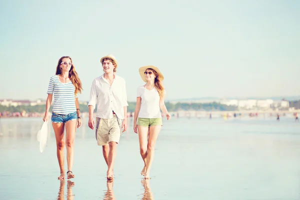 Grupp glada ungdomar gå längs stranden på vackra sommar solnedgång — Stockfoto