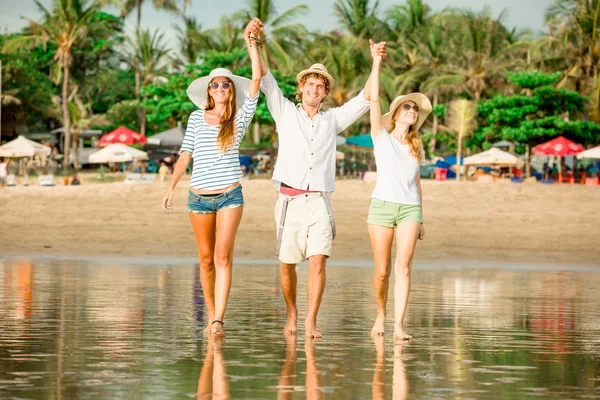 Group of happy young people walking along the beach on beautiful summer sunset — Stock Photo, Image