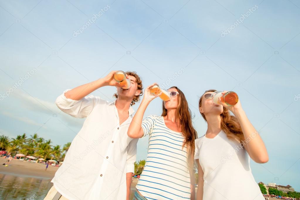 Group of happy young people drinking beer on the beach