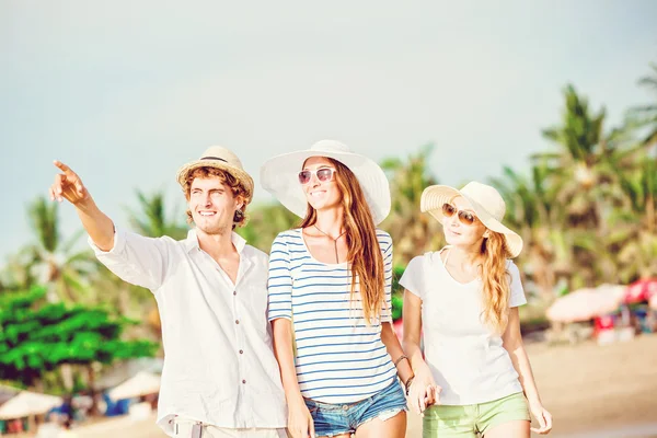 Group of happy young people walking along the beach on beautiful summer sunset — Stock Photo, Image