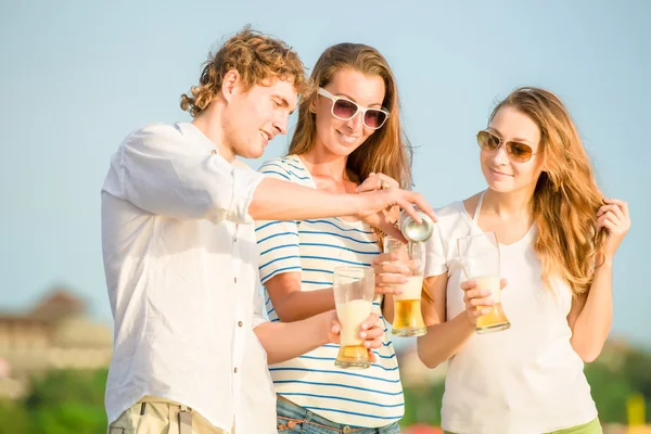 Grupo de jovens felizes bebendo cerveja na praia — Fotografia de Stock