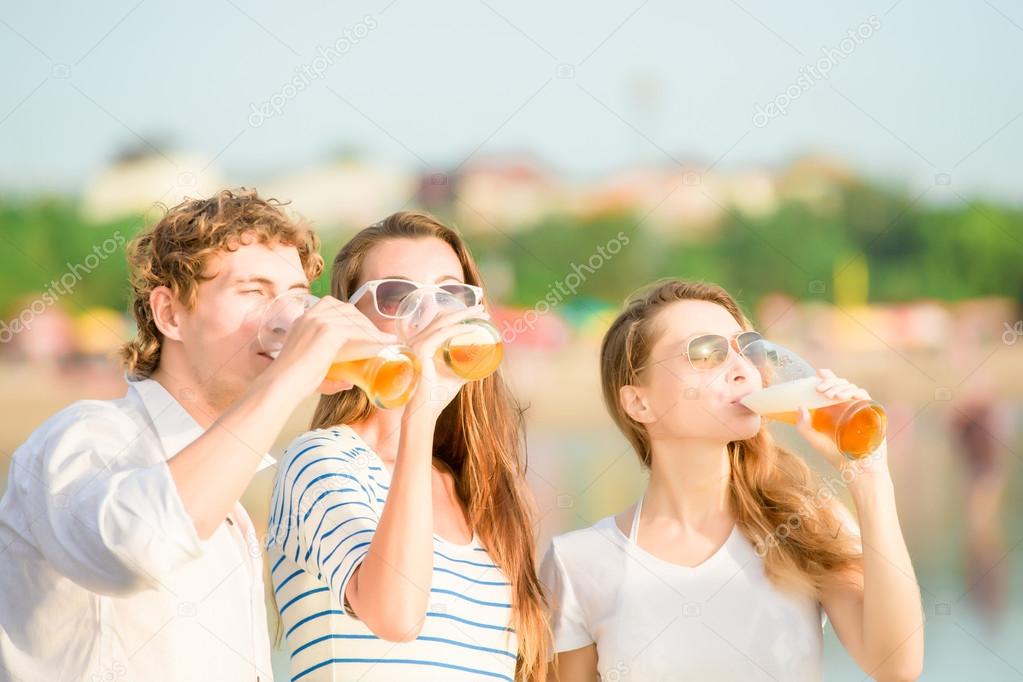 Group of happy young people drinking beer on the beach