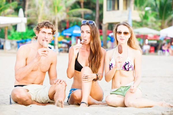 Grupp av glada unga människor äta glass på stranden — Stockfoto