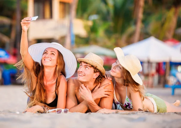 Gruppo di giovani felici sdraiati sulla sabbia bianca della spiaggia e scattare foto di selfie — Foto Stock