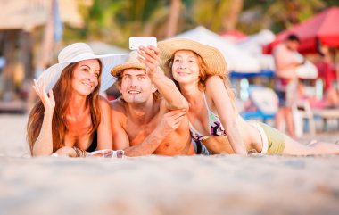 Gençlerin grup wite sahil kumu üzerinde yalan ve selfie fotoğraf çekme mutlu 